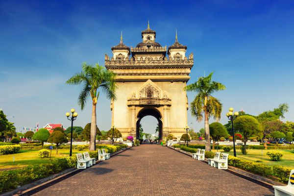 وینتیان لائوس - 7 مه 2016 یکی از جاذبه های اصلی لائوس - بنای یادبود دروازه پاتوکسای که به عنوان دروازه پیروزی یا دروازه پیروزی وینتیان در باغ سبز پس زمینه نخل و آسمان آبی منظره نیز شناخته می شود