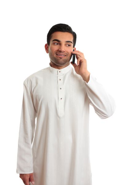 یک مرد شاد خاور میانه عرب قومی با خوشحالی با تلفن همراه صحبت می کند او لباس سنتی سفید کورتا چوب دیشداشا با دکمه های نقره ای منبت کاری شده با یاقوت برمه ای پوشیده است