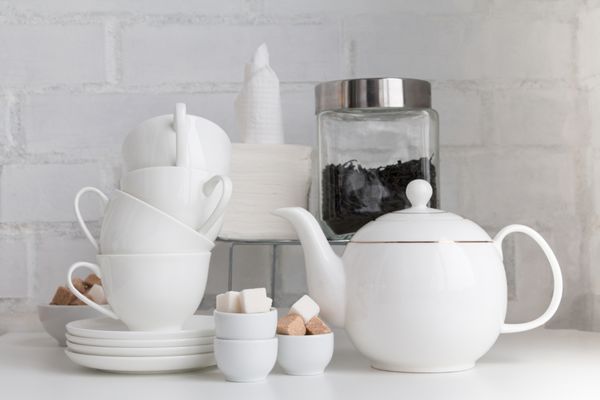مفهوم نوشیدنی چای تکه ای از کافه فضای داخلی رستوران با قوری فنجان چای حبه قند برگ چای دستمال کاغذی نعلبکی روی تخته سفید روی دیوار آجری سفید