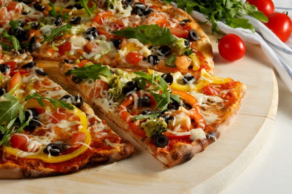 پیتزای گیاهی با سبزیجات در پس زمینه سفید برش پیتزا