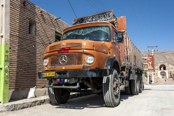 ایران گرمه - 15 اکتبر 2016 کامیون مرسدس بنز قدیمی نارنجی رنگ در خیابانی از روستای واحه ایرانی