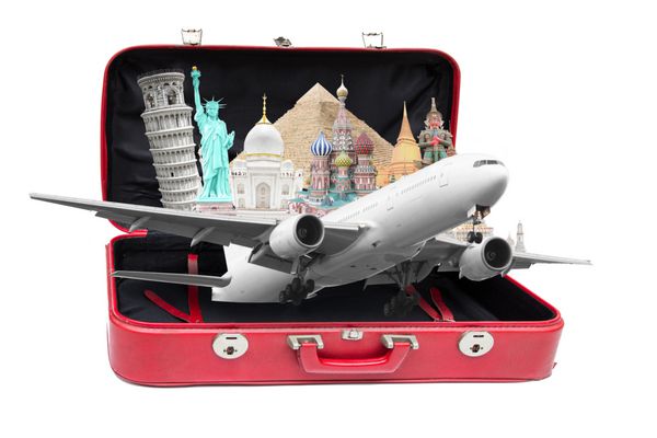 با هواپیما در چمدان قدیمی قرمز رنگ باز در پس زمینه سفید با مسیر برش به سراسر جهان سفر کنید