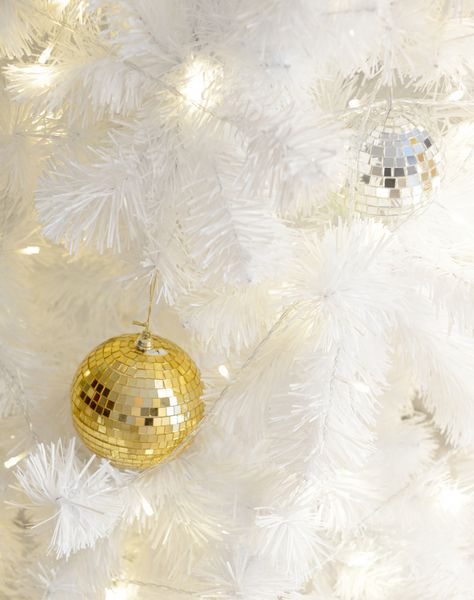 رنگ زینتی طلایی و نقره ای روی درخت کریسمس سفید با نورپردازی تزئینی