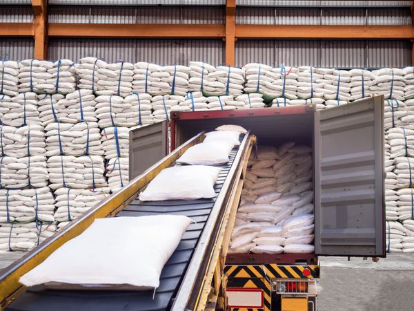 کیسه های سفید قند از انبار در کانتینر برای صادرات پرسنل می شوند