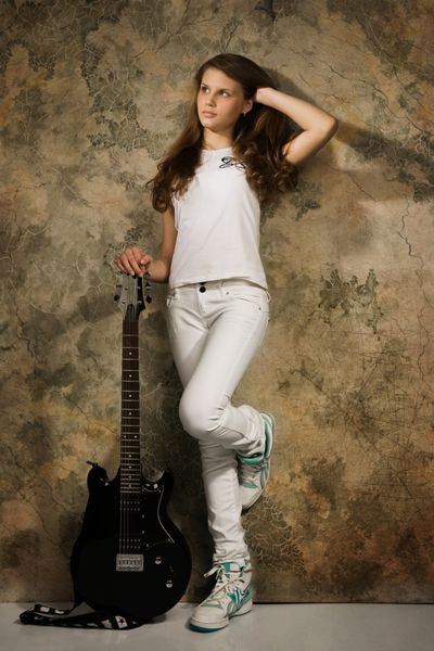 دختر نوجوان با گیتار الکتریک در پس زمینه دیوار