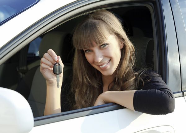 زن جوان شاد و زیبا با کلید ماشین