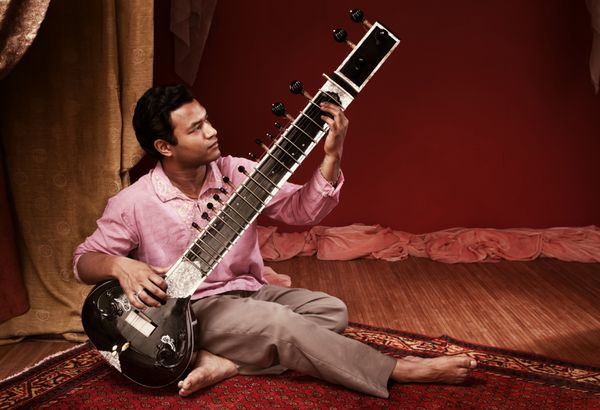 مرد جوان خوش تیپ هندی سیتار می نوازد