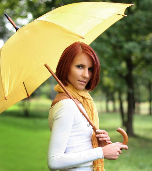 دختر جوان زیبا زیر چتر زرد