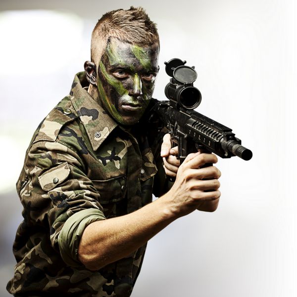 پرتره سرباز جوانی که با تفنگ در پس زمینه نورهای انتزاعی نشانه می رود