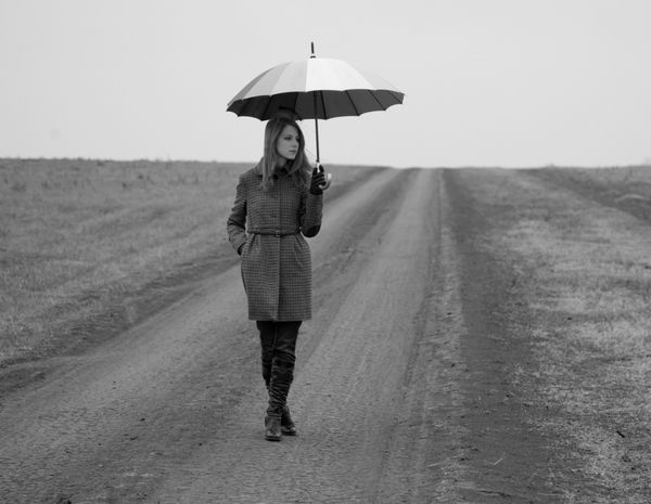 دختر تنها با چتر در جاده روستایی po به سبک قدیمی سیاه و سفید با نویز کم