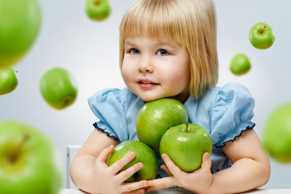 دختر زیبایی که سیب سبز در دست دارد