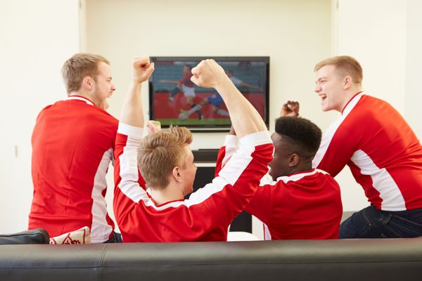 گروهی از طرفداران ورزش در حال تماشای بازی در تلویزیون در خانه