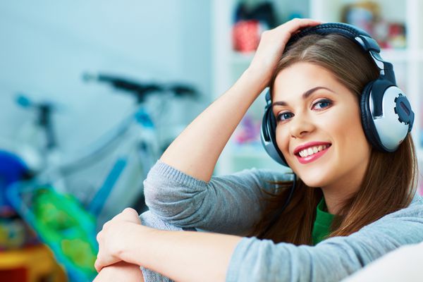 زن خندان در حال گوش دادن به موسیقی با هدفون