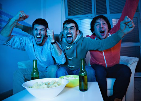 دوستان در حال تماشای ورزش در تلویزیون