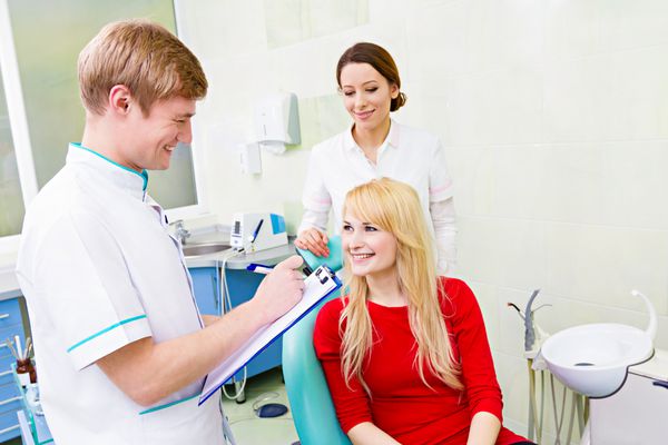 بیمار زن در مطب دندانپزشکی پاسخگویی به سوالات پزشک