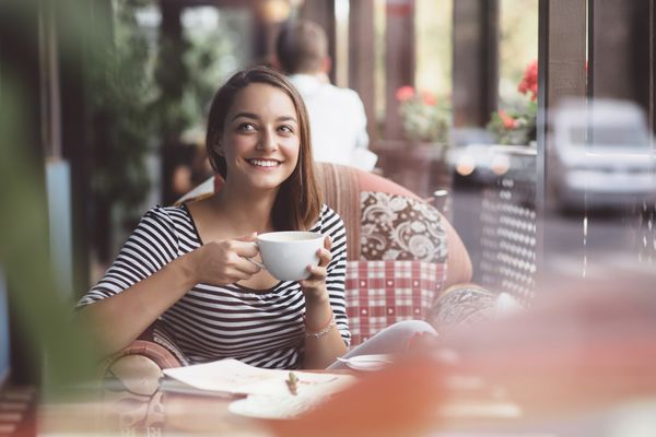 زن جوان در حال نوشیدن قهوه در کافه شهری