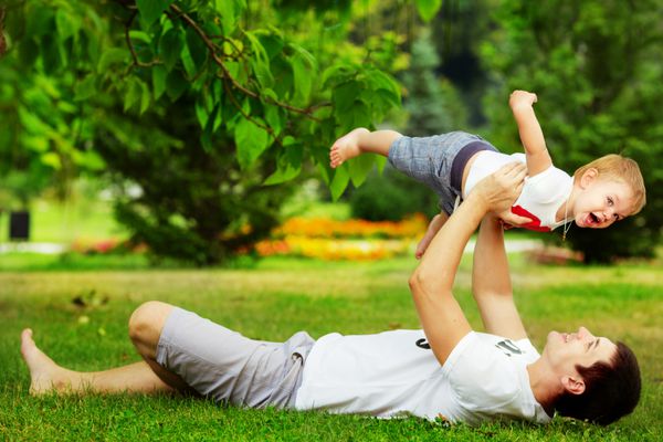 پدر و پسر خوشحال در حال بازی با هم در پارک سبز