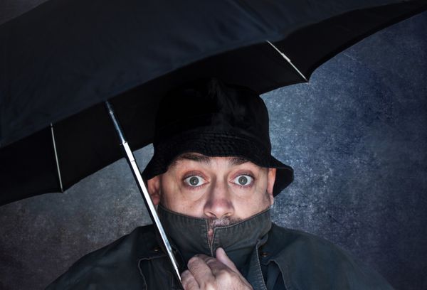 مرد ترسیده زیر چتر