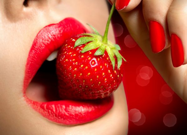 زن در حال خوردن توت فرنگی لبهای قرمز حساس