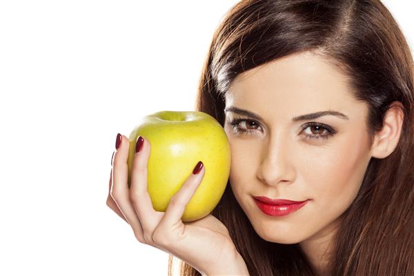 زن جوان زیبا که یک سیب در دست دارد