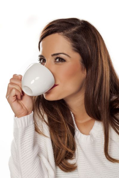 زن جوان زیبا در حال لذت بردن از یک قهوه صبح