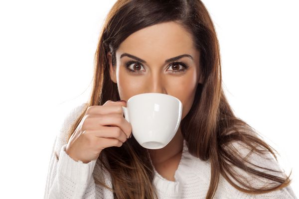 زن جوان زیبا در حال لذت بردن از یک قهوه صبح