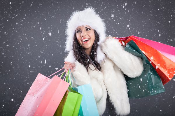 مدل زن با لباس سفید و ساک های خرید رنگی نشانه کریسمس