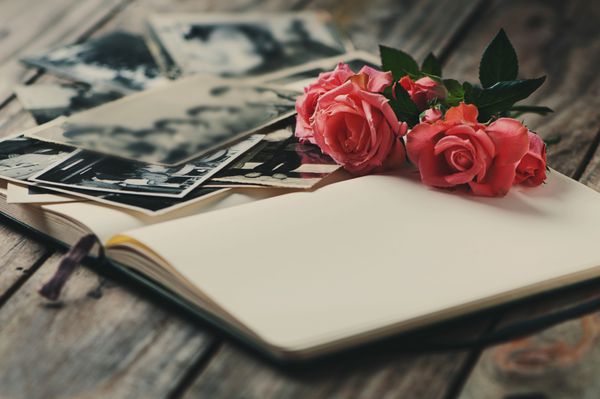 آلبوم عکس با گل رز روی میز چوبی
