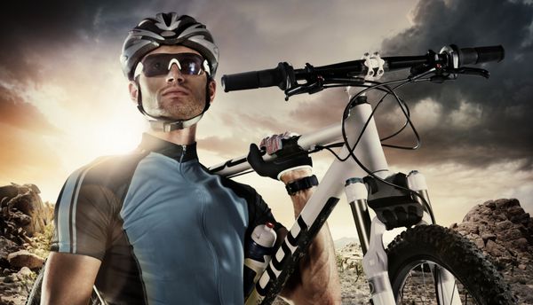 ورزش دوچرخه سوار یک دوچرخه در آسمان دراماتیک حمل می کند