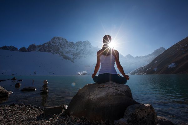 زن جوان در حال تمرین یوگا در دریاچه کوه است