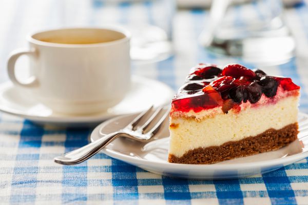 کیک در بشقاب با چنگال و فنجان قهوه