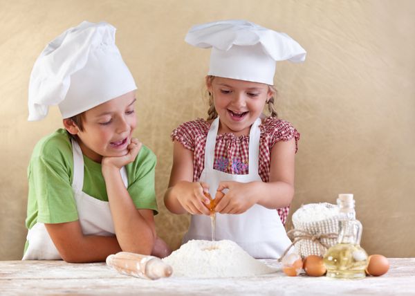 بچه ها خمیر را برای یک کلوچه پیتزا یا پاستا آماده می کنند - از شکستن تخم مرغ ها لذت می برند