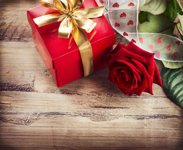  جعبه گل رز و هدیه روی پس زمینه چوبی طراحی هنری حاشیه روز قرمز روی چوب