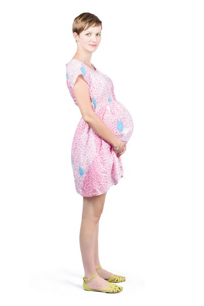 زن باردار زیبا با تمام قد ایستاده روی شکم نوزاد در پس زمینه سفید