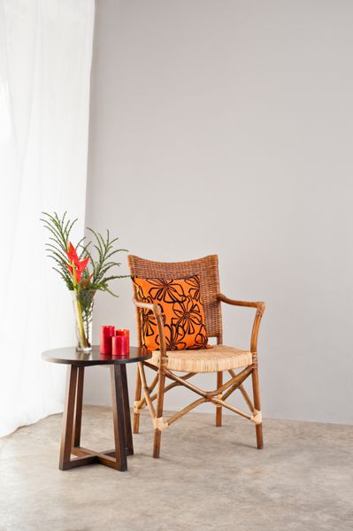 صندلی حصیری با بالش نارنجی رنگ در محیطی روشن