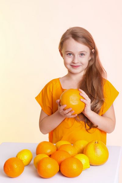 دختر کوچک زیبا با پرتقال لیمو و گریپ فروت