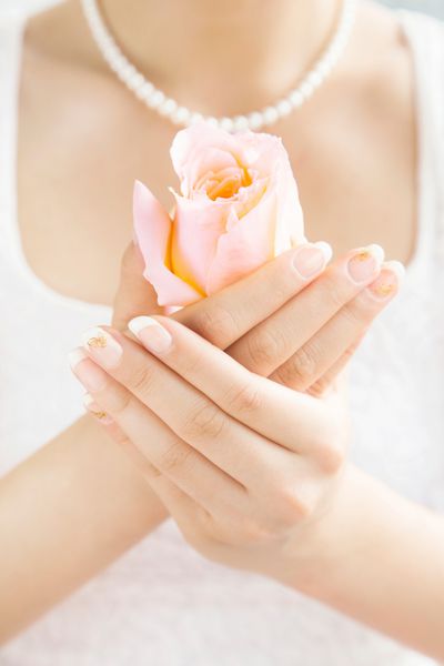 عروسی که یک گل رز در دستانش دارد هنر ناخن زیبا روی ناخن هایش عروسی