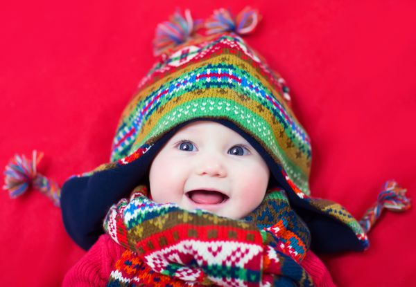 کودک خندان شاد با کلاه و شال رنگارنگ خنده دار