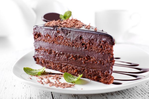 کیک شکلاتی خوشمزه روی بشقاب روی میز در زمینه روشن