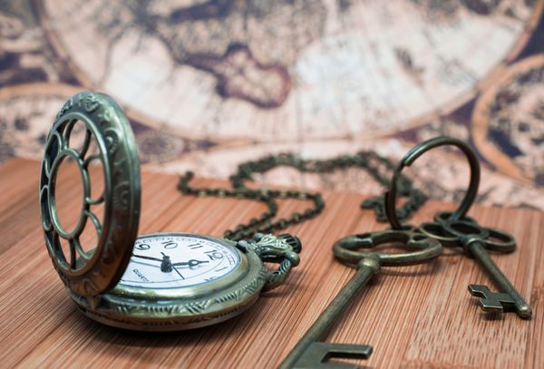 ساعت ساعت جیبی گرانج عتیقه کلیدهای اسکلت روی میز چوبی و پس زمینه نقشه باستانی