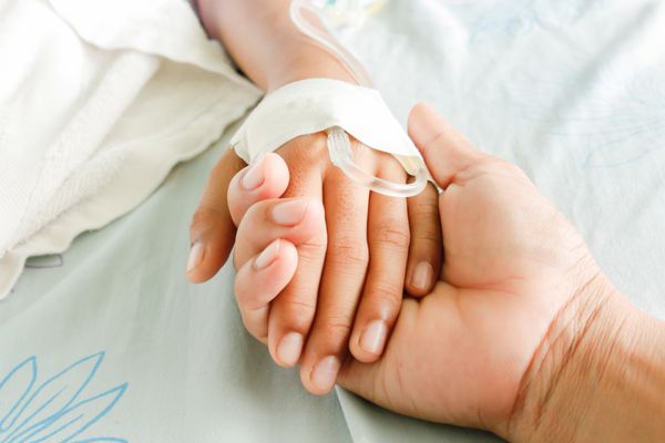 مادری که دست کودکی را گرفته که بیماران تب دار لوله IV دارند