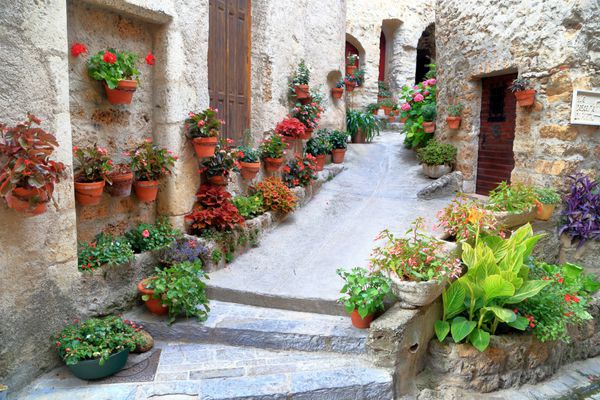 ساختمان‌های سنگی تزئین‌شده با گلدان‌های گل در خیابانی در داخل دهکده قرون وسطایی Saint Guilhem le desert languedoc roussillon فرانسه