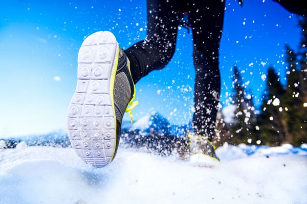 پاهای یک دونده جوان بیرون در طبیعت زمستانی