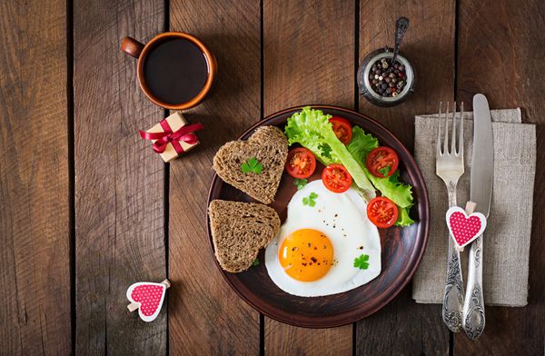 صبحانه در روز - تخم مرغ سرخ شده و نان به شکل قلب و سبزیجات تازه نمای بالا