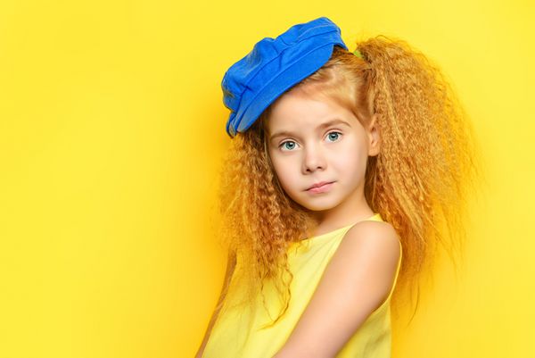 دختر کوچک شاد با موهای زیبا روی پس زمینه زرد سبک بچه گانه مدل مو