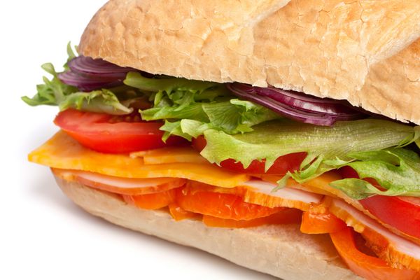 ساندویچ باگت بلند با کاهو تکه های سبزیجات تازه ژامبون سینه بوقلمون و پنیر