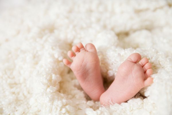 پاهای یک نوزاد تازه متولد شده ناز در پتوی سفید گرم دوران کودکی پاهای کوچک یک نوزاد دختر یا پسر کودک تازه متولد شده در خواب
