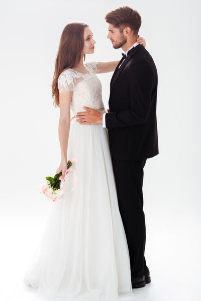 پرتره تمام قد از تازه عروس های زیبا با دسته گل پس زمینه سفید جدا شده