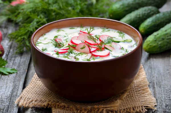 سوپ سرد ماست تابستانی با تربچه خیار و شوید روی میز چوبی okroshka