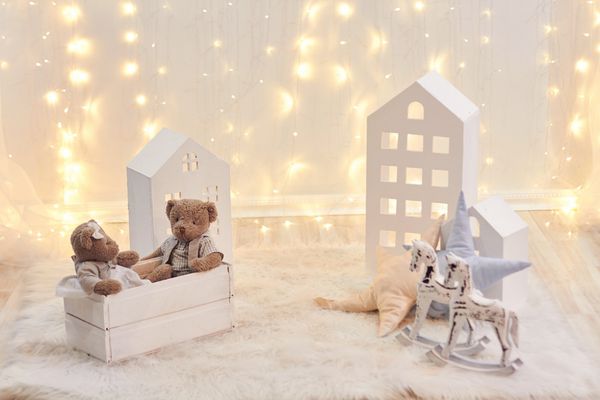 اسباب بازی های کودک و خانه اسباب بازی در پس زمینه ای از چراغ های کریسمس دکوراسیون تعطیلات اتاق کودک سال نو خرس و اسب چوبی